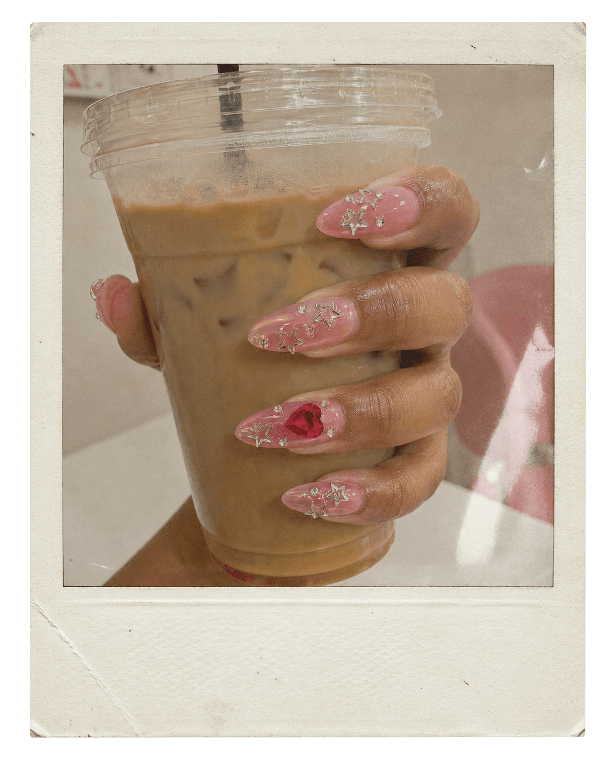 Vintage instant photo of pink ombre nails holding an iced coffee.