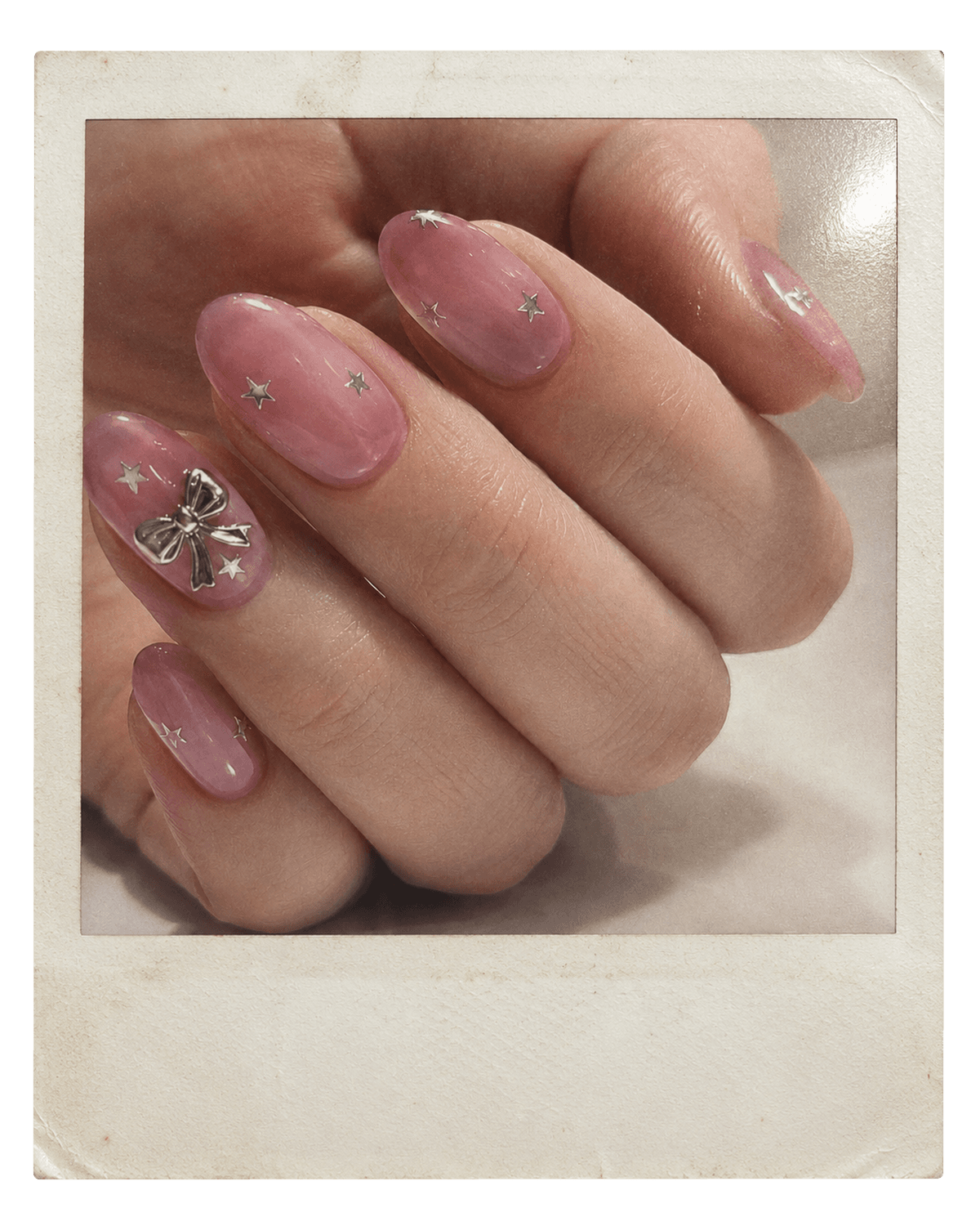 Vintage instant photo of pink jelly nails with silver bows and stars.